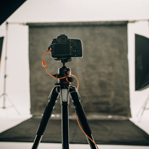 Studio setup with black background and studio flash lights with a DSLR camera on a tripod.